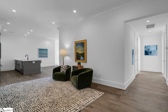 living room with crown molding, wood-type flooring, and sink