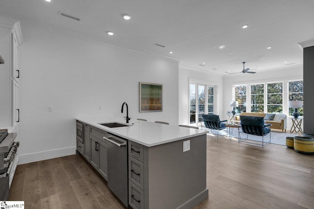 kitchen featuring sink, light wood-type flooring, stainless steel dishwasher, and light stone counters