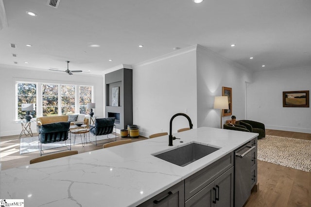 kitchen featuring light stone countertops, sink, dark hardwood / wood-style flooring, stainless steel dishwasher, and crown molding