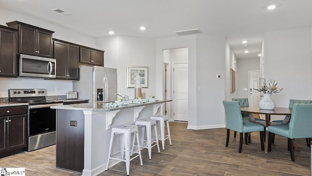 kitchen with hardwood / wood-style floors, stainless steel appliances, and dark brown cabinets