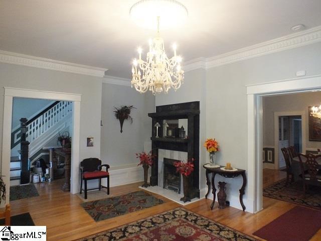 living room with an inviting chandelier, ornamental molding, and hardwood / wood-style flooring