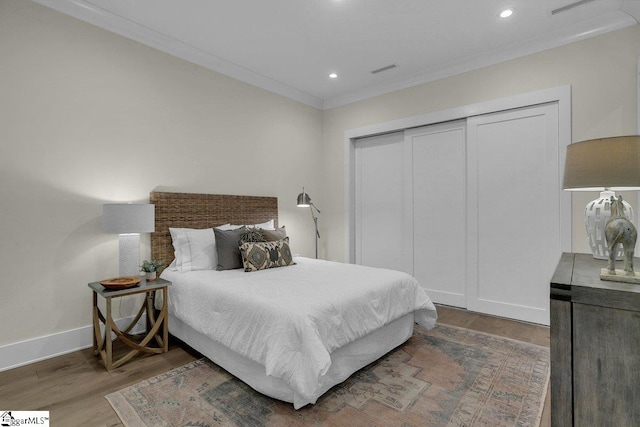 bedroom featuring crown molding, dark wood-type flooring, and a closet