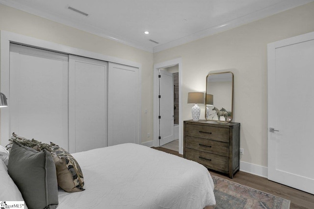 bedroom featuring a closet, dark hardwood / wood-style flooring, and ornamental molding