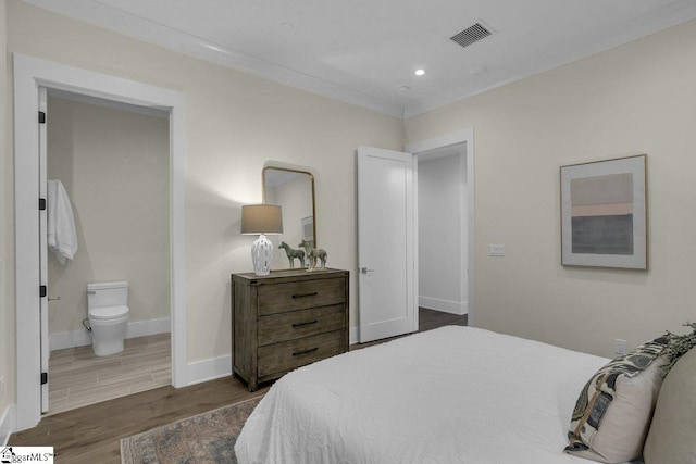 bedroom featuring ensuite bath and dark hardwood / wood-style floors