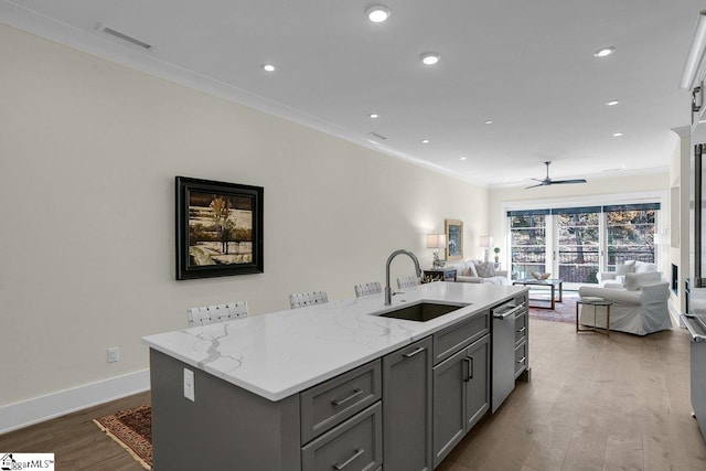 kitchen featuring an island with sink, gray cabinets, stainless steel dishwasher, and sink