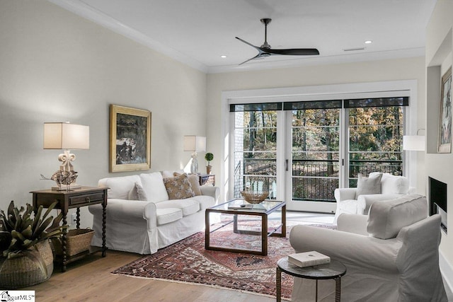 living room with hardwood / wood-style flooring, ceiling fan, and crown molding