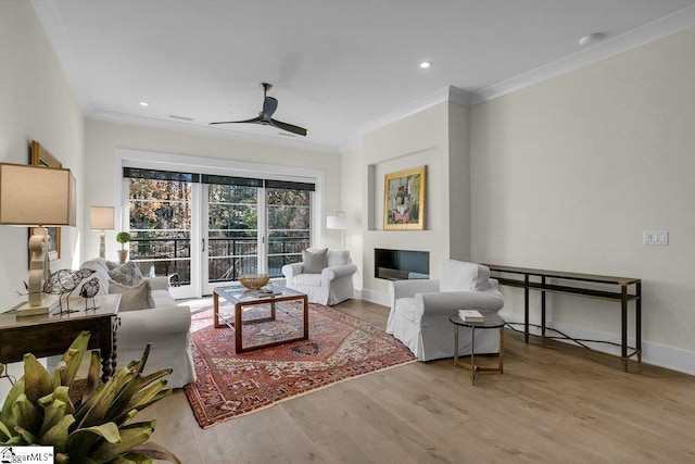 living room featuring light hardwood / wood-style floors, ceiling fan, and crown molding