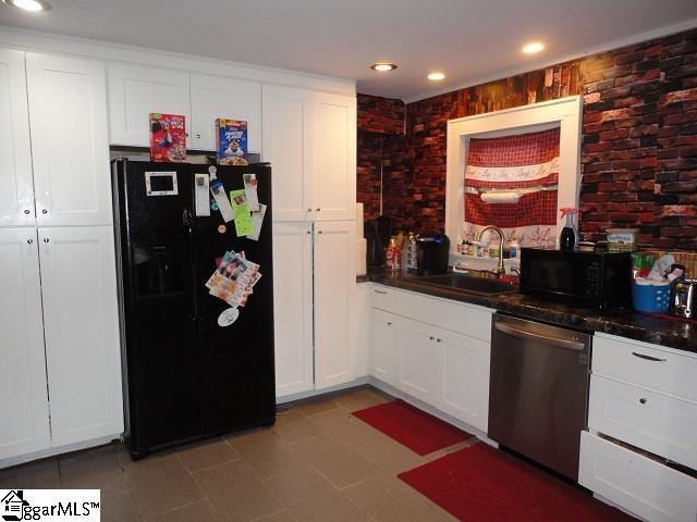 kitchen with light tile floors, white cabinetry, black appliances, and sink