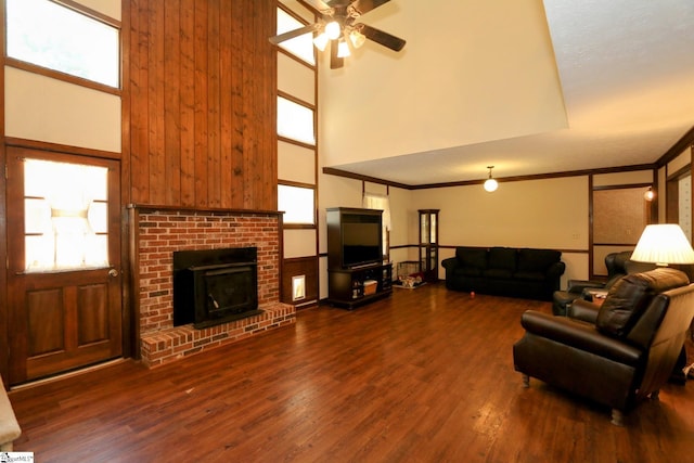 living room featuring a high ceiling, ceiling fan, dark hardwood / wood-style flooring, and a brick fireplace