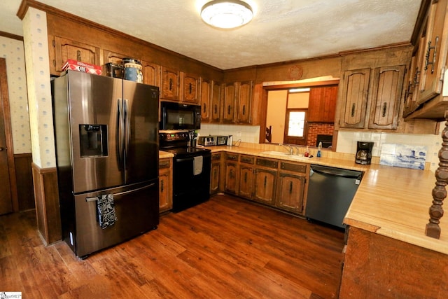 kitchen with dark wood-type flooring, black appliances, sink, a textured ceiling, and crown molding