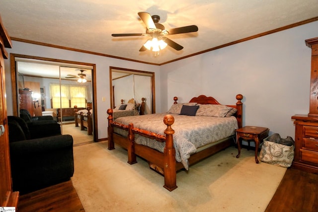 bedroom featuring crown molding, ceiling fan, and two closets