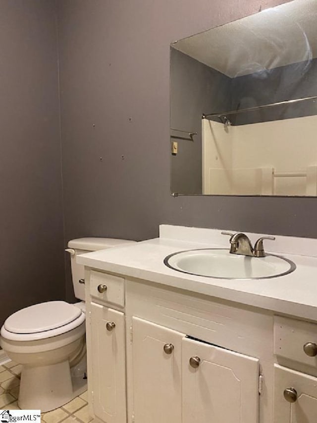 bathroom featuring tile flooring, toilet, and vanity