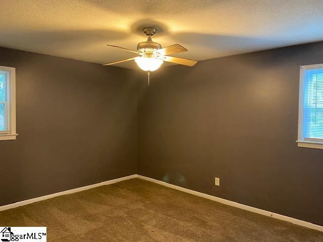 carpeted empty room featuring ceiling fan and a textured ceiling