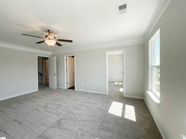 unfurnished bedroom with light colored carpet, a spacious closet, ornamental molding, and ceiling fan