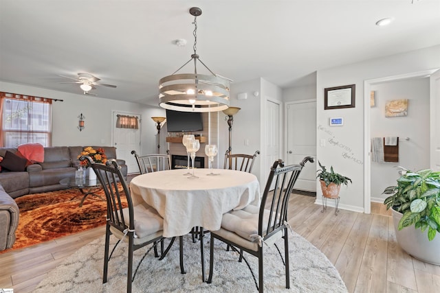 dining area with ceiling fan with notable chandelier and light wood-type flooring