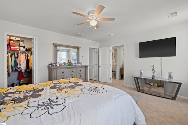 bedroom with light carpet, a spacious closet, a closet, and ceiling fan