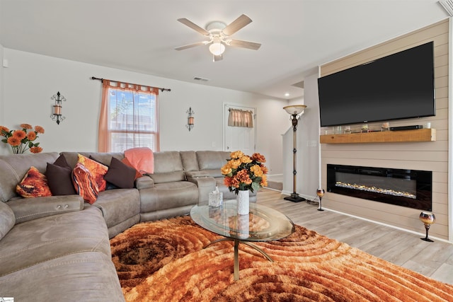 living room with light hardwood / wood-style floors, ceiling fan, and a fireplace