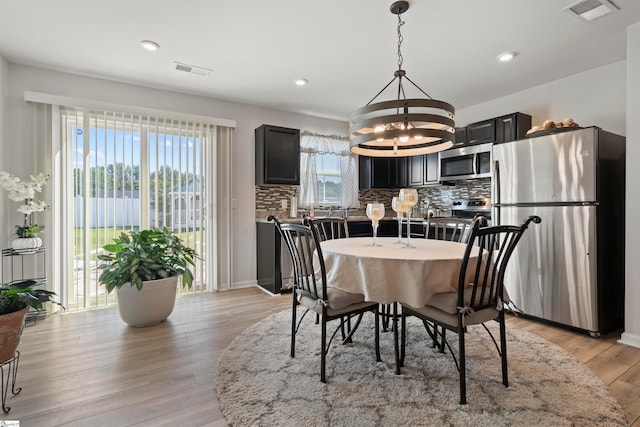 dining space with light hardwood / wood-style flooring, a chandelier, and a healthy amount of sunlight