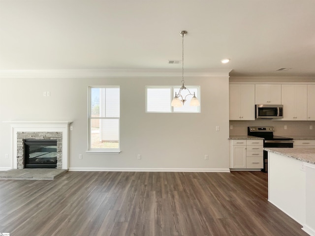 kitchen with dark hardwood / wood-style flooring, an inviting chandelier, appliances with stainless steel finishes, light stone counters, and backsplash