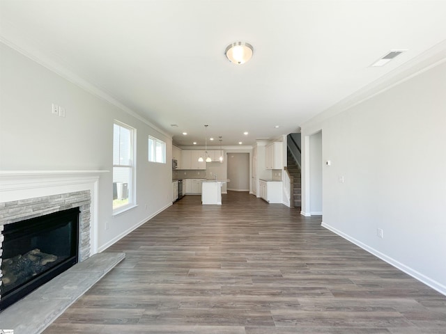 unfurnished living room featuring a stone fireplace, dark hardwood / wood-style flooring, and ornamental molding