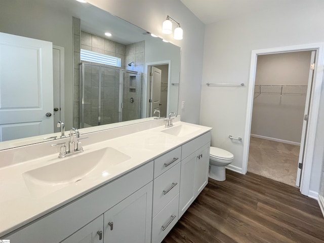 bathroom featuring hardwood / wood-style floors, a shower with shower door, dual vanity, and toilet