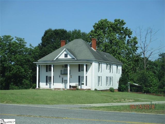 greek revival house featuring covered porch and a front lawn