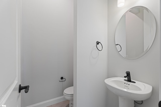 bathroom with baseboards, a sink, toilet, and wood finished floors