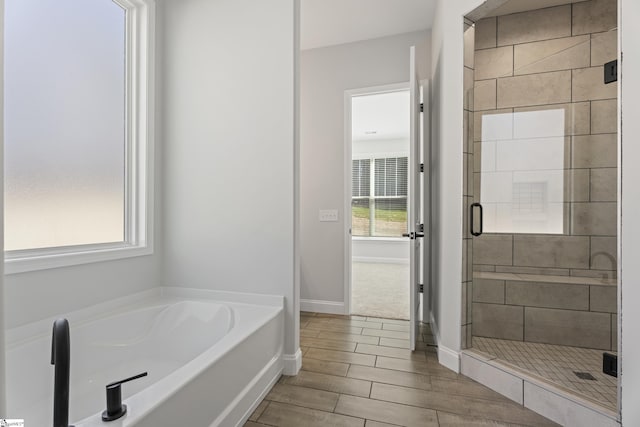 bathroom featuring wood tiled floor, a shower stall, baseboards, and a bath