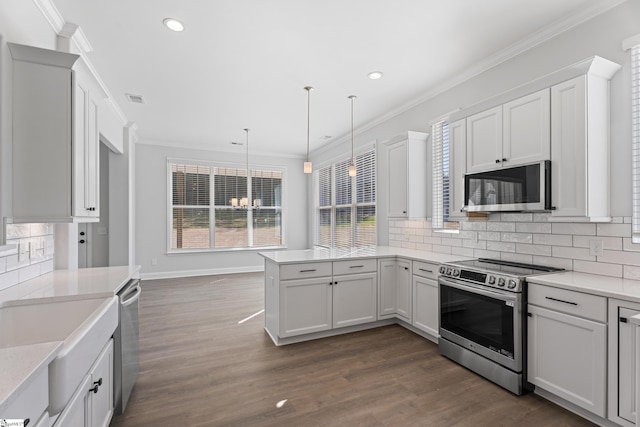 kitchen with a peninsula, appliances with stainless steel finishes, decorative light fixtures, and white cabinetry