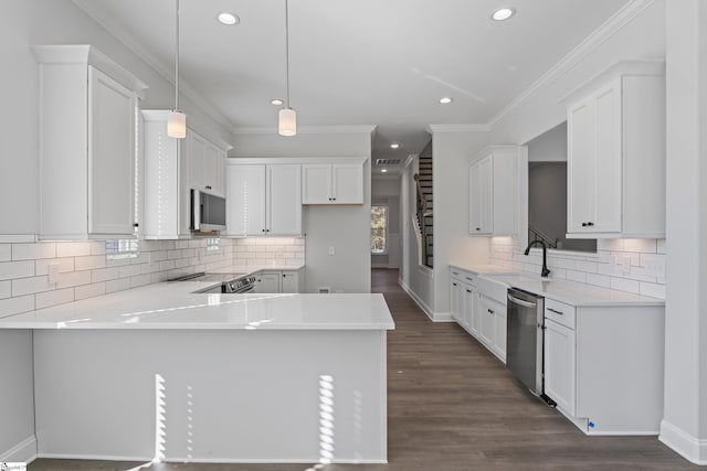 kitchen with light countertops, appliances with stainless steel finishes, a peninsula, and white cabinetry