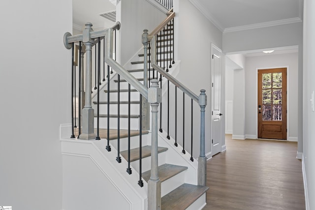 stairway featuring ornamental molding, visible vents, baseboards, and wood finished floors