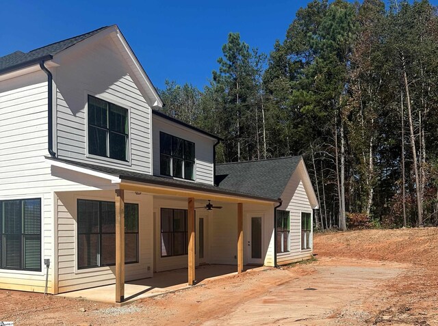 view of property exterior with ceiling fan, roof with shingles, and a patio area