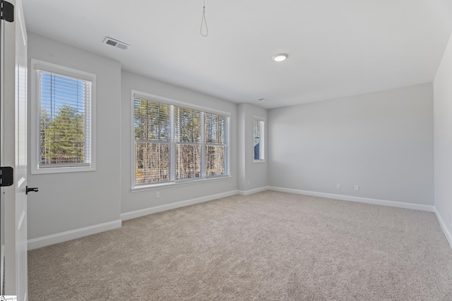 spare room with light colored carpet, visible vents, and baseboards