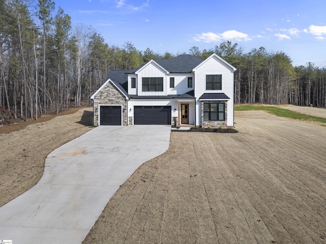 modern farmhouse style home featuring board and batten siding, a standing seam roof, a view of trees, stone siding, and driveway