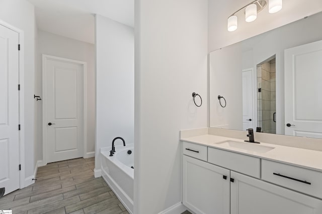 full bathroom featuring wood finish floors, vanity, baseboards, a shower stall, and a bath