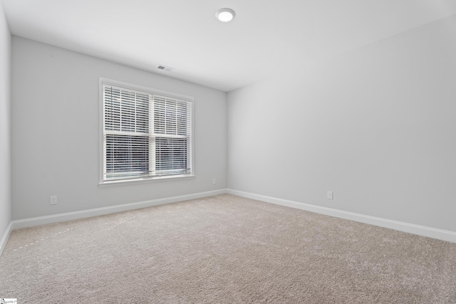 carpeted spare room featuring visible vents and baseboards