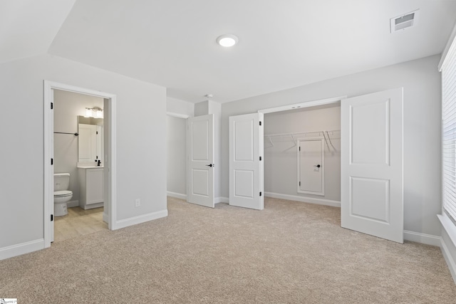 unfurnished bedroom featuring a closet, visible vents, ensuite bathroom, light carpet, and baseboards