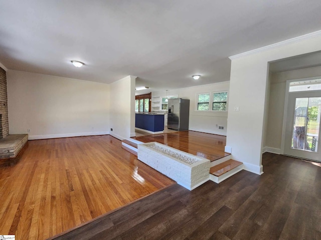 unfurnished living room with a brick fireplace, dark hardwood / wood-style flooring, and a wealth of natural light