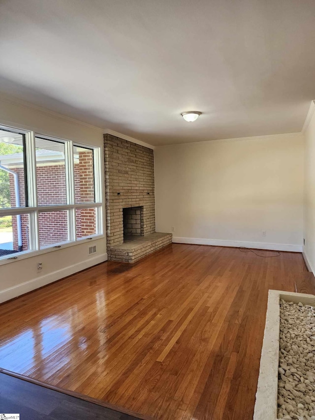 unfurnished living room with hardwood / wood-style floors, a healthy amount of sunlight, and a brick fireplace