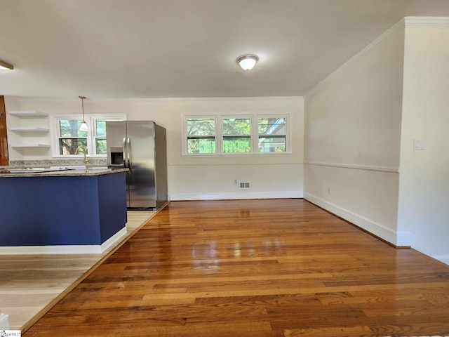 interior space with stainless steel fridge with ice dispenser, stone counters, wood-type flooring, and a wealth of natural light