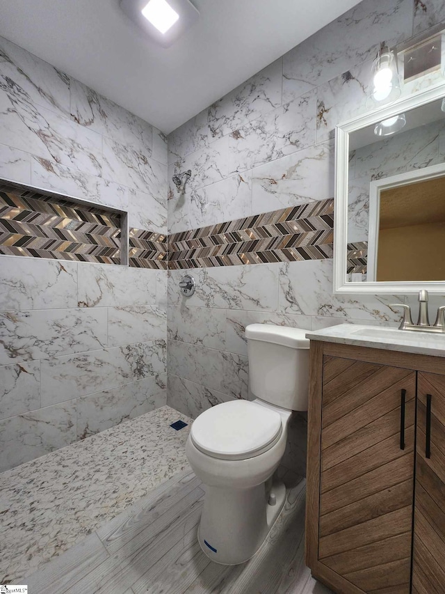 bathroom featuring tile walls, toilet, tiled shower, tile flooring, and vanity