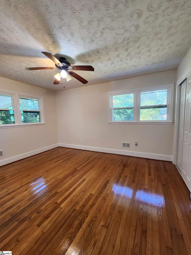 spare room featuring ceiling fan, dark hardwood / wood-style floors, and a textured ceiling