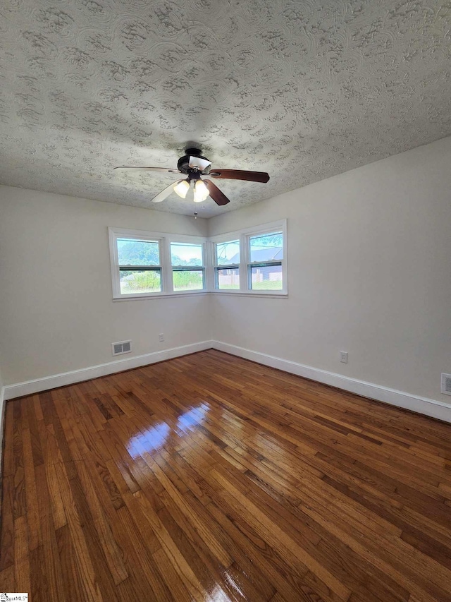 unfurnished room with ceiling fan, a textured ceiling, and dark hardwood / wood-style floors