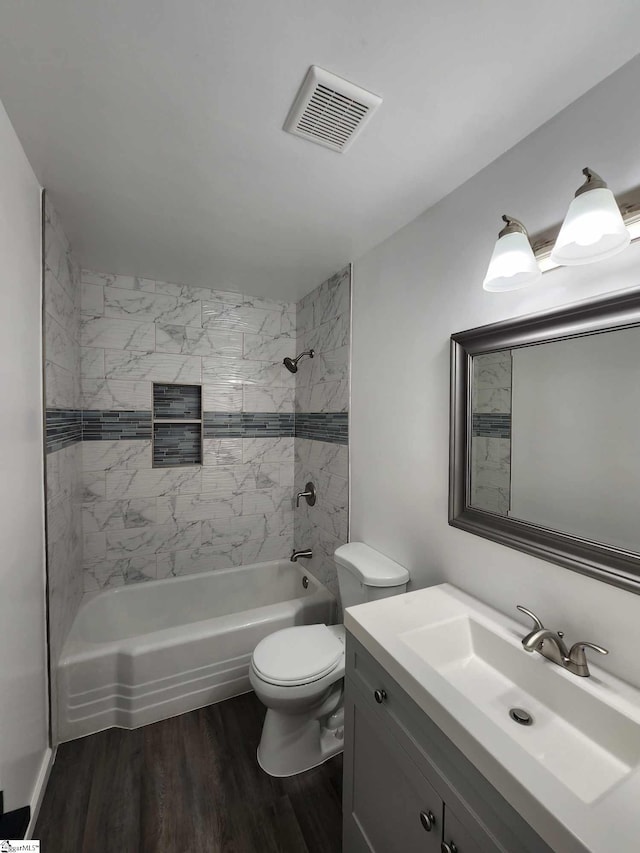 full bathroom featuring tiled shower / bath combo, hardwood / wood-style floors, vanity, and toilet