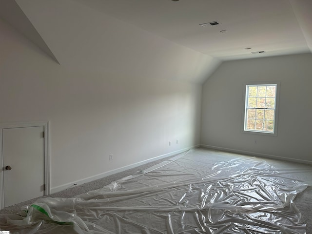 additional living space featuring vaulted ceiling and light colored carpet