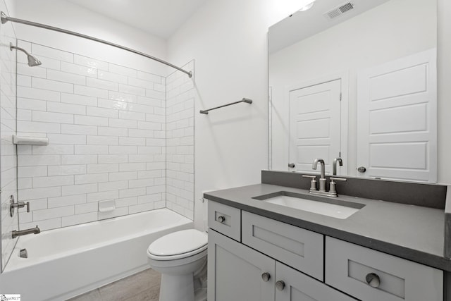 full bathroom featuring tile patterned flooring, tiled shower / bath, vanity, and toilet