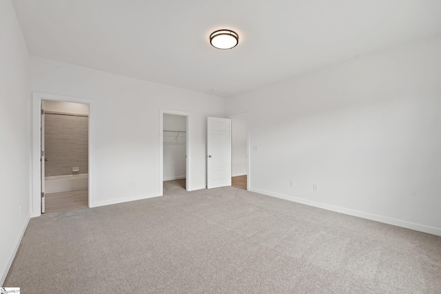 unfurnished bedroom featuring carpet, connected bathroom, a spacious closet, and a closet