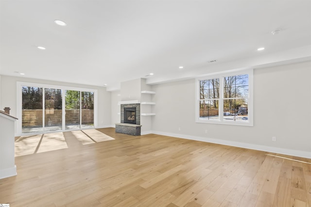 unfurnished living room featuring light hardwood / wood-style flooring and a brick fireplace