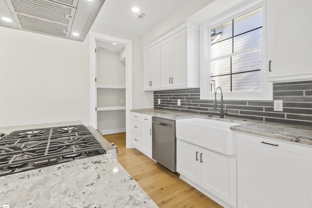 kitchen featuring light stone countertops, stainless steel appliances, sink, white cabinets, and light hardwood / wood-style floors