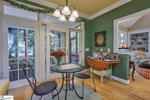 dining area featuring crown molding, light wood-type flooring, and an inviting chandelier